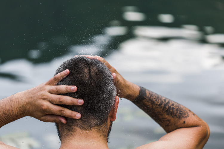 Bild zeigt Mann im Wasser mit nassen Haaren im Winter, der über eine Haartransplantation nachdenkt